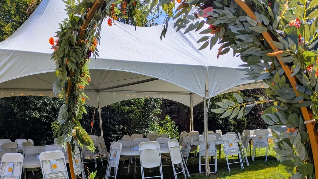Professional tent installation crew setting up white frame tent in residential backyard for private event